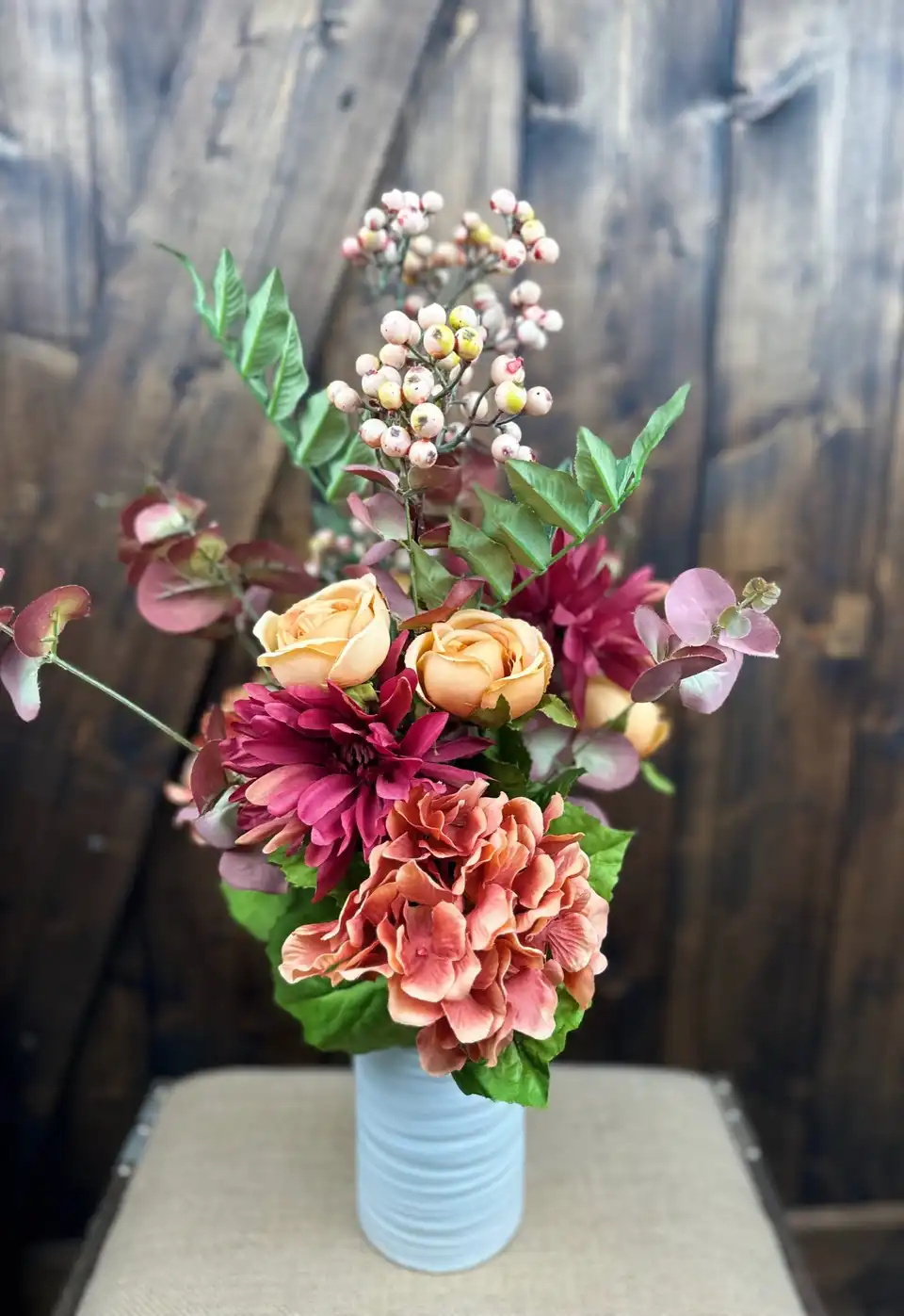 Burgundy dahlias, peach roses and coral hydrangea in a glass vase