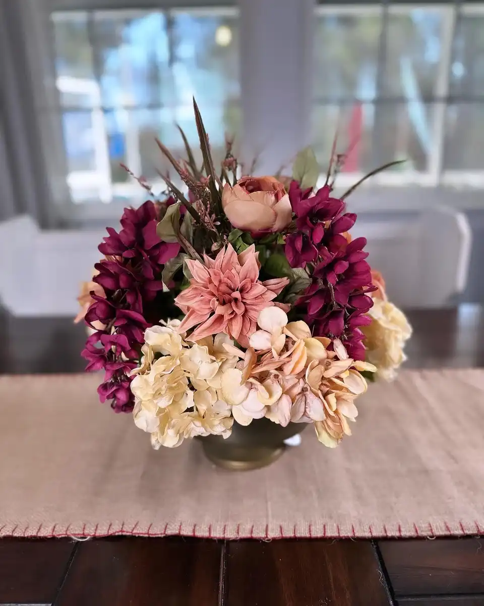 Dusty pink dahlias, burgundy mums and peach hydrangea in a brass vase