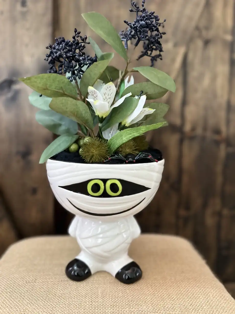 Playful Halloween mummy planter filled with faux greenery and lilies