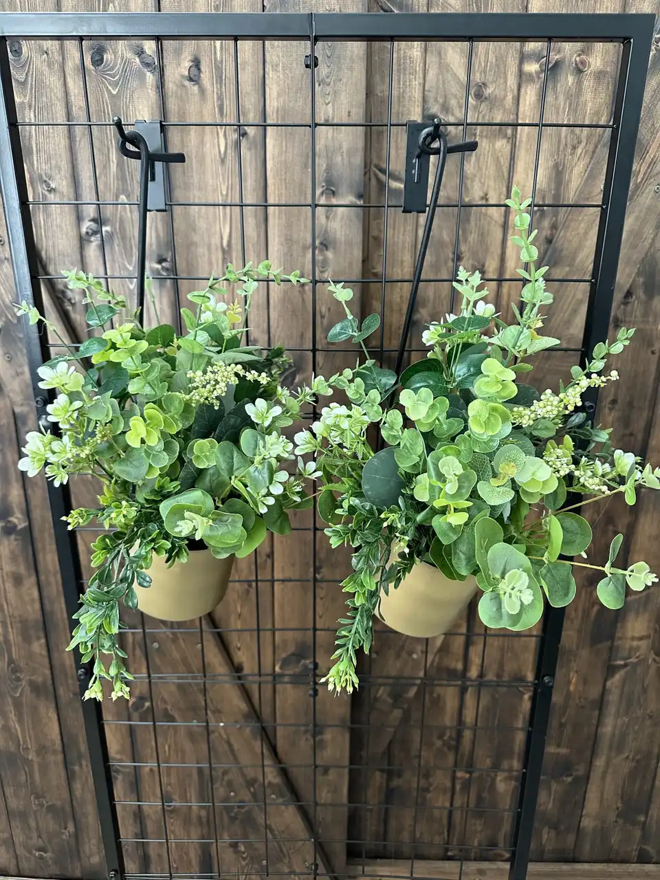 Pair of hanging wall planters overflowing with faux eucalyptus greenery